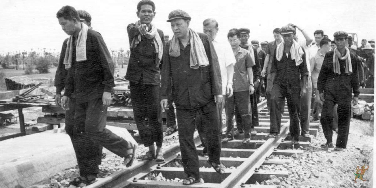 កម្មាភិបាលជាន់ខ្ពស់ខ្មែរក្រហម និងគណៈប្រតិភូនៃសាធារណរដ្ឋប្រជាមានិតចិន នៅលើផ្លូវរថភ្លើងក្នុងអំឡុងចុង ឆ្នាំ១៩៧៥។ ពីឆ្វេងទៅស្តាំ៖ វន វ៉េត ឧបនាយករដ្ឋមន្ត្រី និងជារដ្ឋមន្ត្រីពាណិជ្ជកម្ម, ម៉ី ប្រាង (ចង្អុលមកមុខ) ប្រធានគណៈកម្មាធិការទំនាក់ទំនង, អៀង សារី ឧបនាយករដ្ឋមន្ត្រី និងជារដ្ឋមន្ត្រីការបរទេស, ឧត្ដមសេនីយ៍ តឹង ឃុនសាន (ពាក់អាវព័ណ៍សខាងក្រោយ អៀង សារី) ប្រធានអ្នកជំនាញការចិនប្រចាំកម្ពុជាប្រជាធិបតេយ្យ និងសមមិត្ត ស៊ូ (ពាក់វ៉ែនតាឈរខាងក្រោយឧត្ដមសេនីយ៍ តឹង ឃុនសាន) អ្នកបកប្រែភាសាចិន។ ប្រភព៖ បណ្ណសារមជ្ឈមណ្ឌលឯកសារកម្ពុជា។